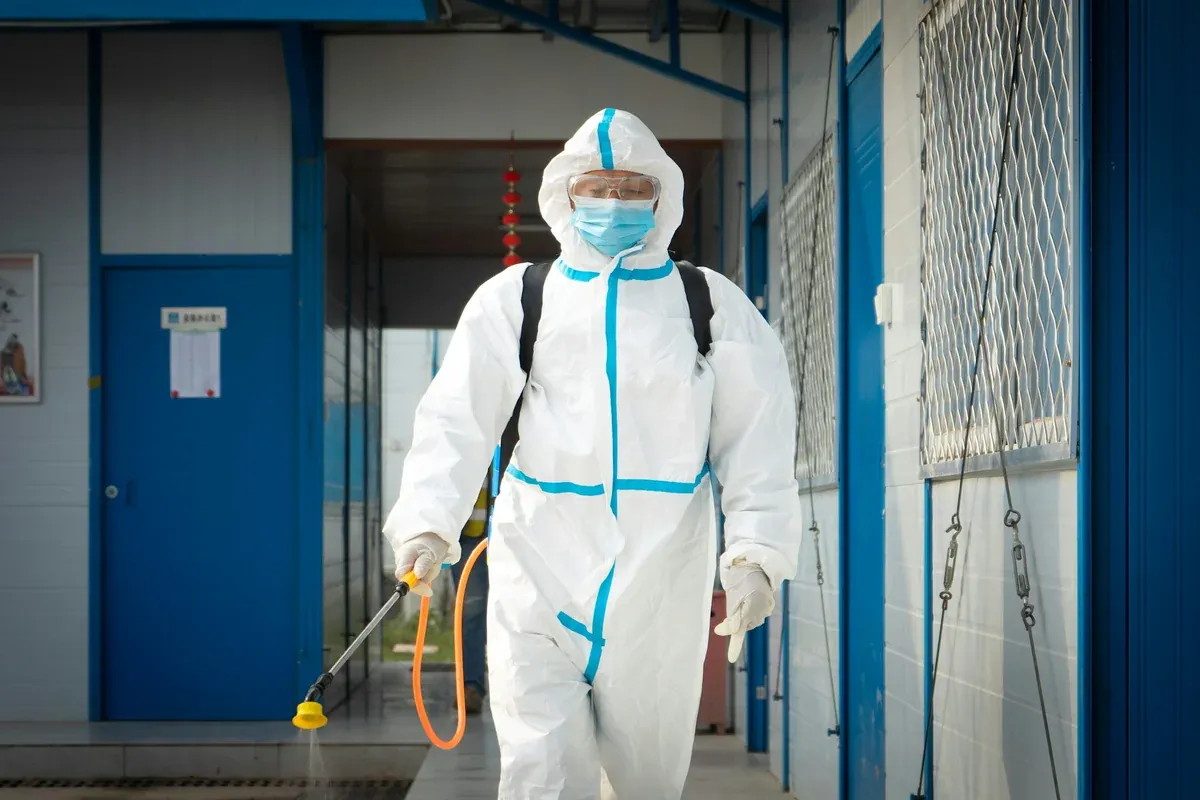 Sure Shot technician in protective suit applying an exterior treatment with a sprayer